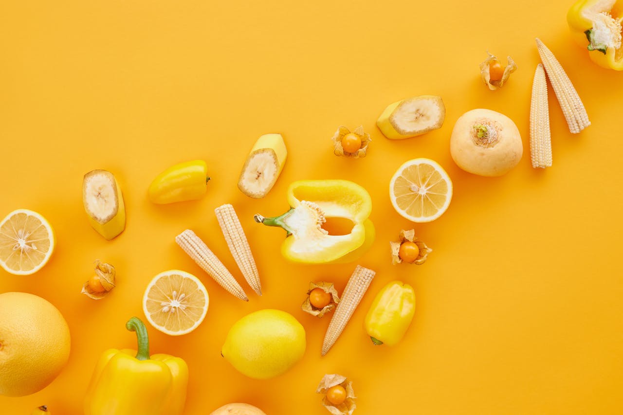 A colorful flatlay featuring yellow fruits and vegetables against a vibrant background.